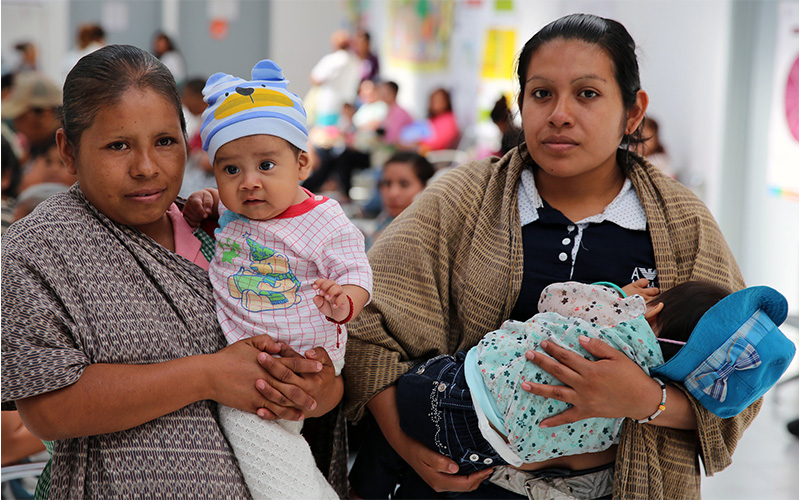 Two women holding babies in their arms.