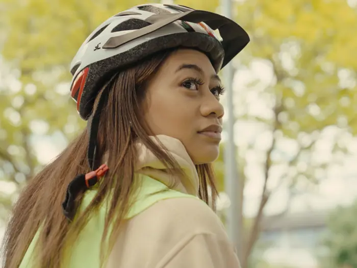 A person wearing a bicycle helmet with a tree in the background.