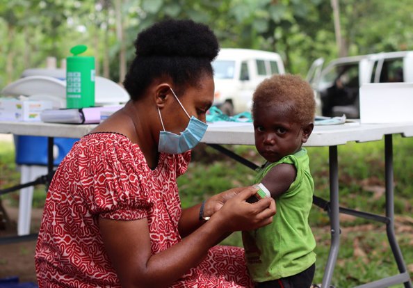 A parent or caregiver tending to a child's arm in Papua New Guinea.