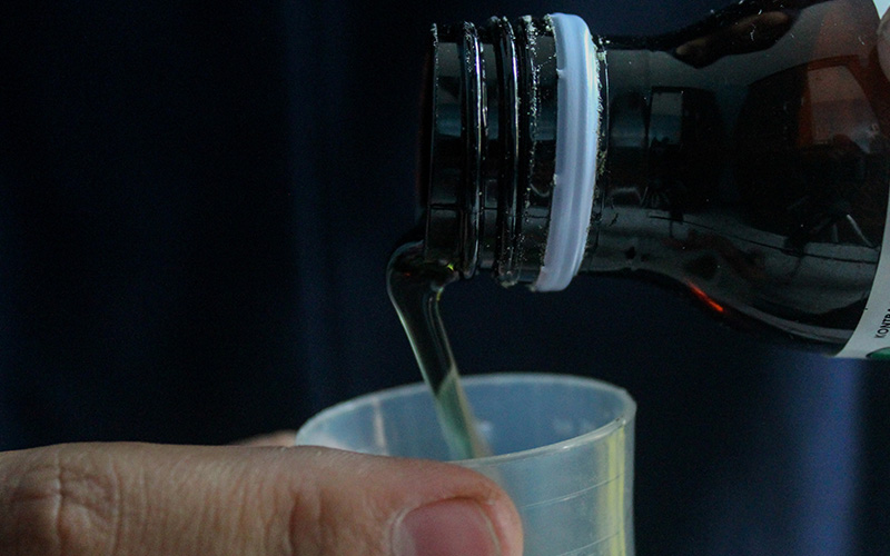 Someone pouring medicine into a cup