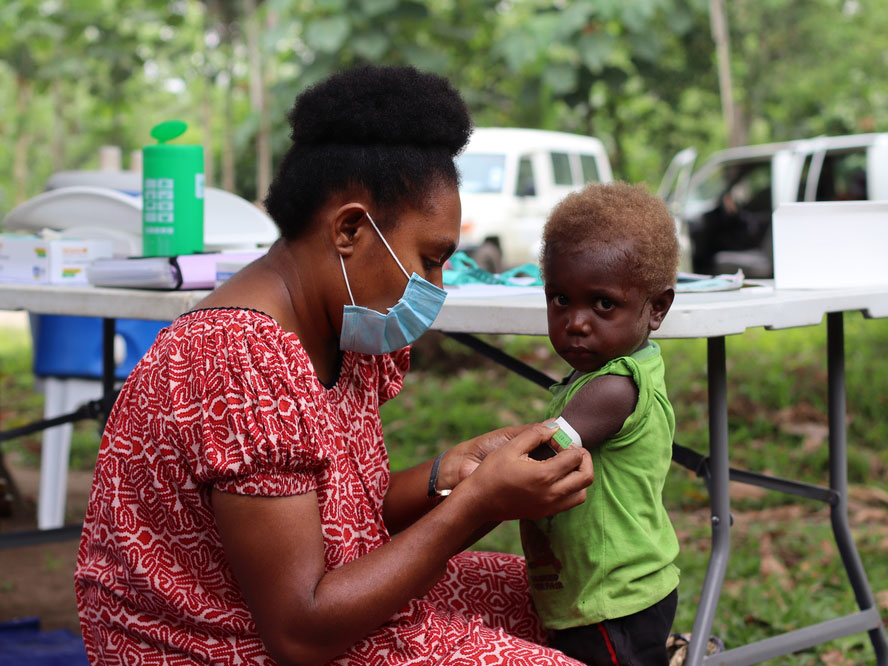 A parent or caregiver tending to a child's arm in Papua New Guinea.
